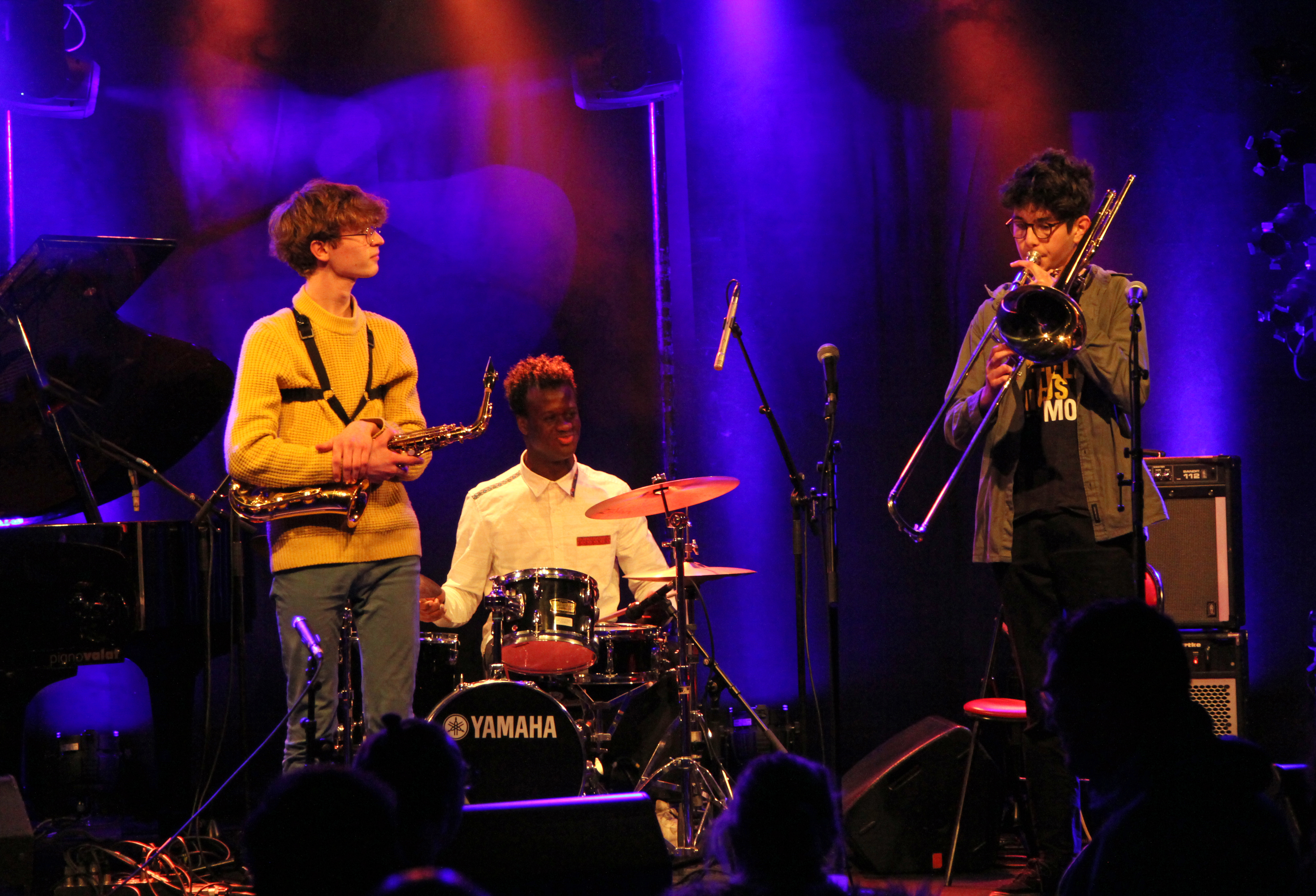 Photo montrant 3 jeunes musiciens de jazz sur scène (saxophone, batterie, trombone)