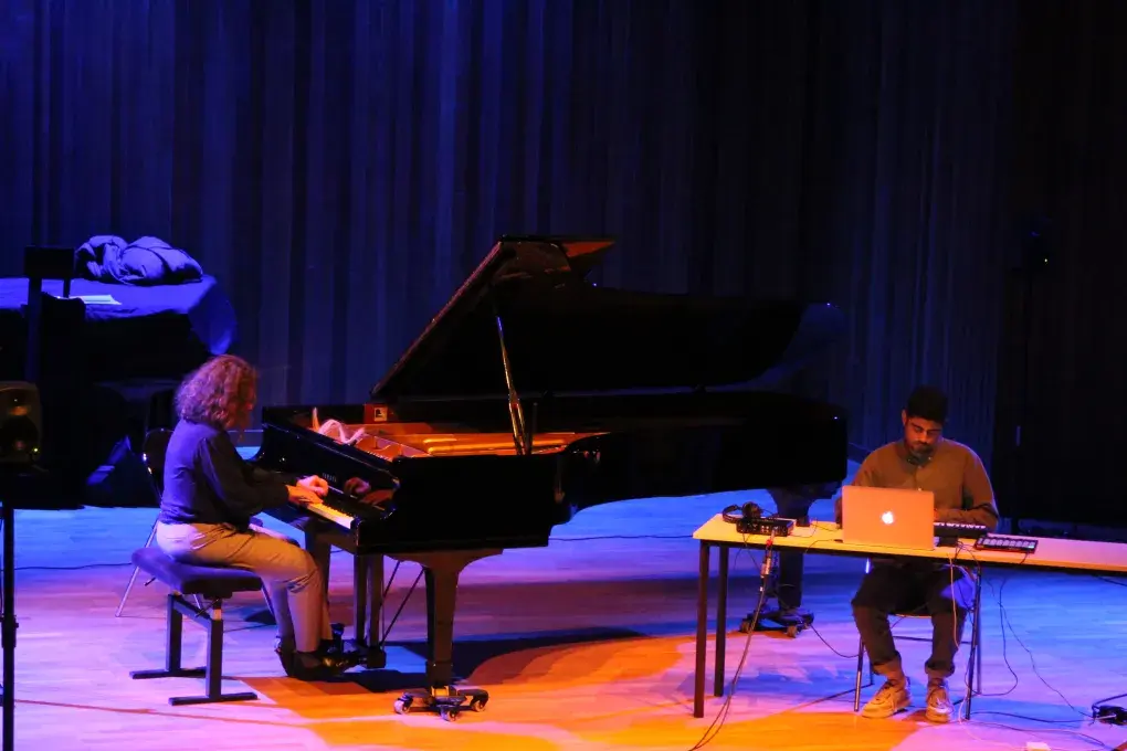 Photo monrant une pianiste jouant sur scène en duo avec un musicien émettant du son depuis un  ordinateur