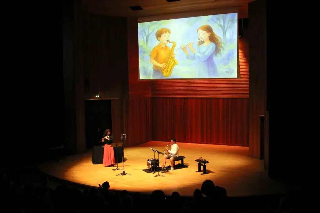 Photo montrant deux instrumentistes (flûte traversière et saxophone) jouant sur une scène