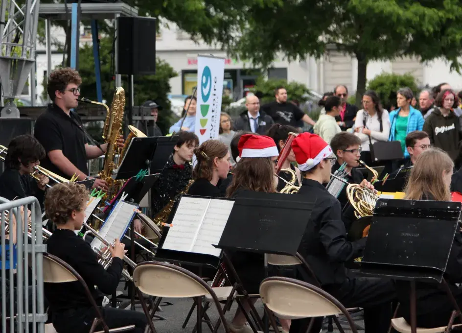 Orchestre d'harmonie du conservatoire se produisant en concert en extérieur à la Fête de la musique devant du public.