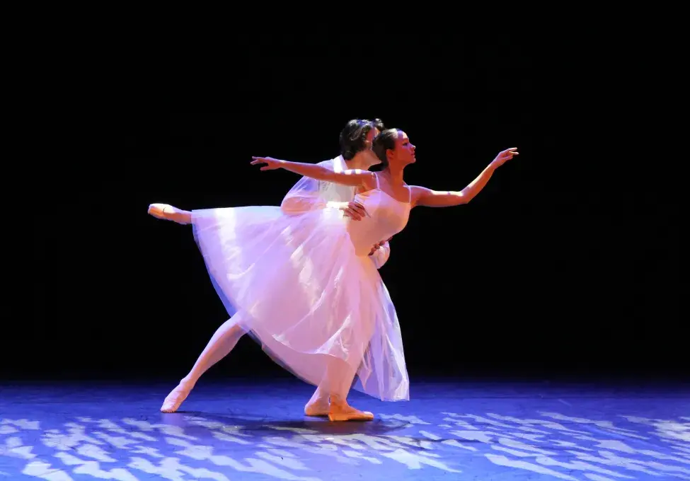 Photo montrant un duo de danseuse et danseur classiques en spectacle effectuant un porté sur une scène.