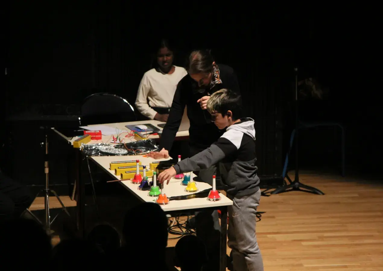 Photo montrant une professeure expliquant le processus de musique électronique à des élèves sur une scène