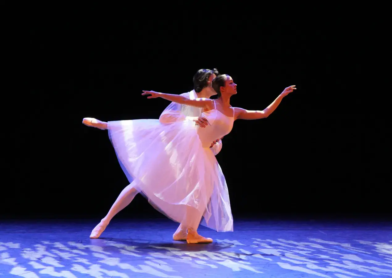 Photo montrant un duo de danseuse et danseur classiques en spectacle effectuant un porté sur une scène.
