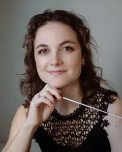 Photo montrant une jeune femme posant avec une baguette de cheffe d'orchestre