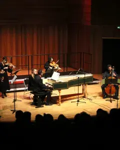 Photo montrant des musiciens jouant sur scène : clavecin, flûte, contrebasse, violoncelle, alto et violon.
