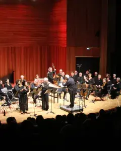 Photo montrant des musiciennes et musiciens d'orchestre jouant sur scène.