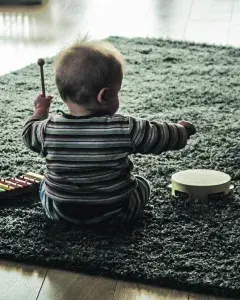 Photo montrant un bébé de dos jouant avec un tambourin
