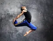 Jeune danseur effectuant une figure chorégraphique dansée en sautant en l'air