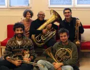 Photo représentant 5 professeurs d'instruments assis tous ensemble avec chacun leur instrument (2 trompettes, 1 tuba, 1 trombone, 1 cor)