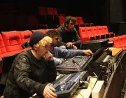 Photo montrant 3 agents technique du conservatoire actionnant les boutons d'une console numérique pour régler le son et la lumière dans l'auditorium.