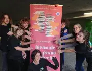 Photo montrant 7 personnes souriantes, posant leur mains comme sur un piano sur l'affiche de la biennale de piano collectif de Saint-Denis.