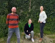 Photo montrant trois personnes posant en souriant en extérieur.