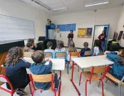 Photo montrant deux adultes debout s'adressant à des élèves assis dans une salle de ocurs de musique