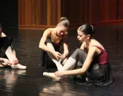 Photo montrant trois danseuses préparant leurs chaussons de danse