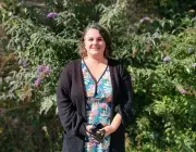 Photo portrait d'Anne-Cécile, posant debout en extérieur dans un jardin