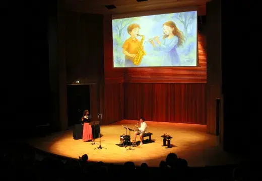 Photo montrant deux instrumentistes (flûte traversière et saxophone) jouant sur une scène