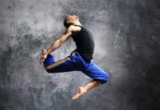 Jeune danseur effectuant une figure chorégraphique dansée en sautant en l'air