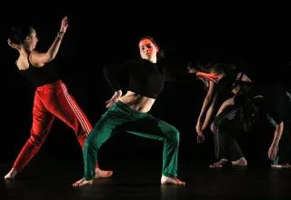 Photo montrant quatre jeunes femmes réalisant une chorégraphie de danse contemporaine sur une scène