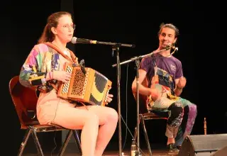Photo montrant deux élèves en concert sur scène : une accordéoniste et un joueur de tambourin