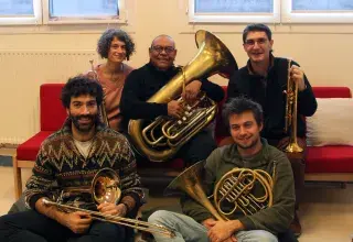 Photo représentant 5 professeurs d'instruments assis tous ensemble avec chacun leur instrument (2 trompettes, 1 tuba, 1 trombone, 1 cor)
