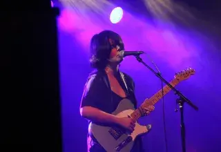 Photo montrant une femme jouant de la guitare électrique et chantant sur une scène
