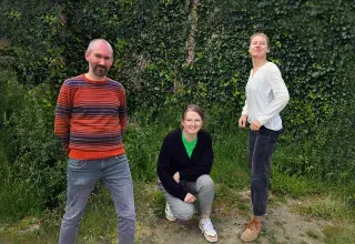 Photo montrant trois personnes posant en souriant en extérieur.