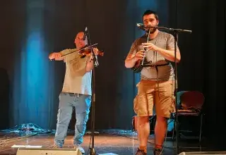 Photo montrant un violoniste et un sonneur jouant sur une scène de spectacle