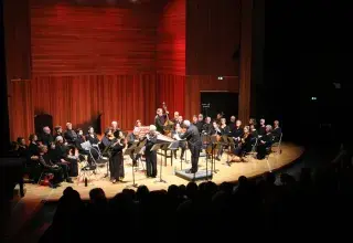 Photo montrant des musiciennes et musiciens d'orchestre jouant sur scène.