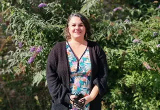Photo portrait d'Anne-Cécile, posant debout en extérieur dans un jardin