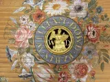 Photo représentant le détail peint de l'intérieur d'un clavecin : des fleurs et un ange doré.