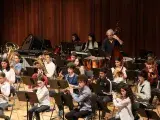 Image montrant des élèves instrumentistes (bois cuivres et contrebasse) jouant en ensemble sur une scène.